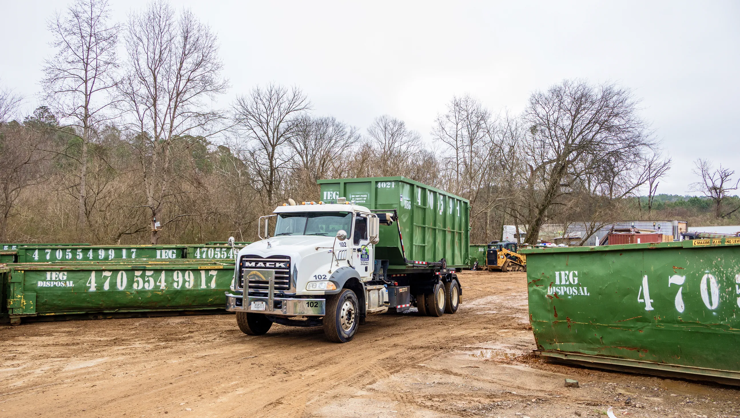 A truck driving a dumpster though a field