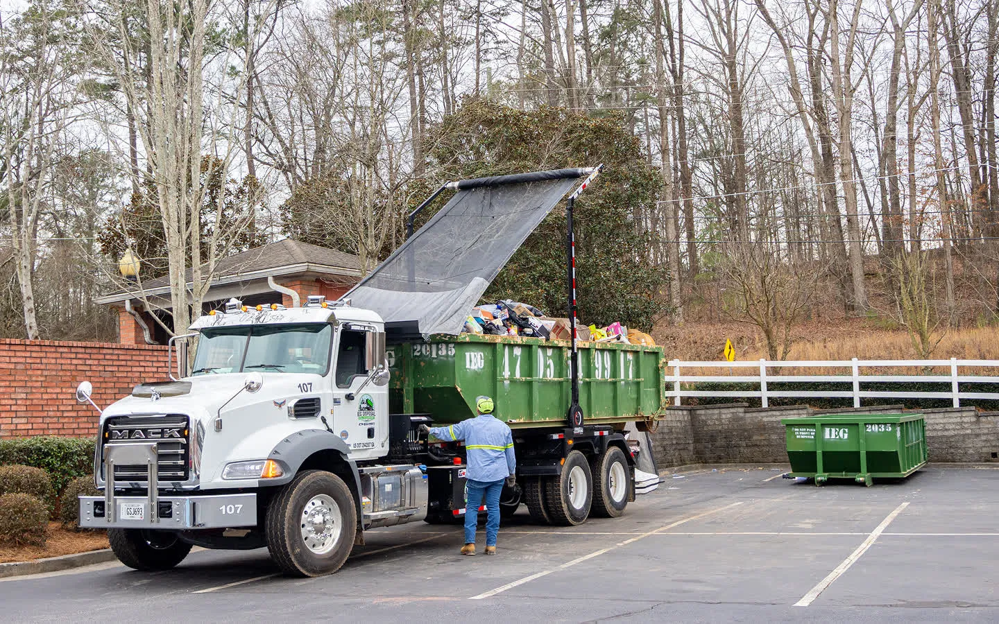 A dumpsters being dropped off in front of a house.
