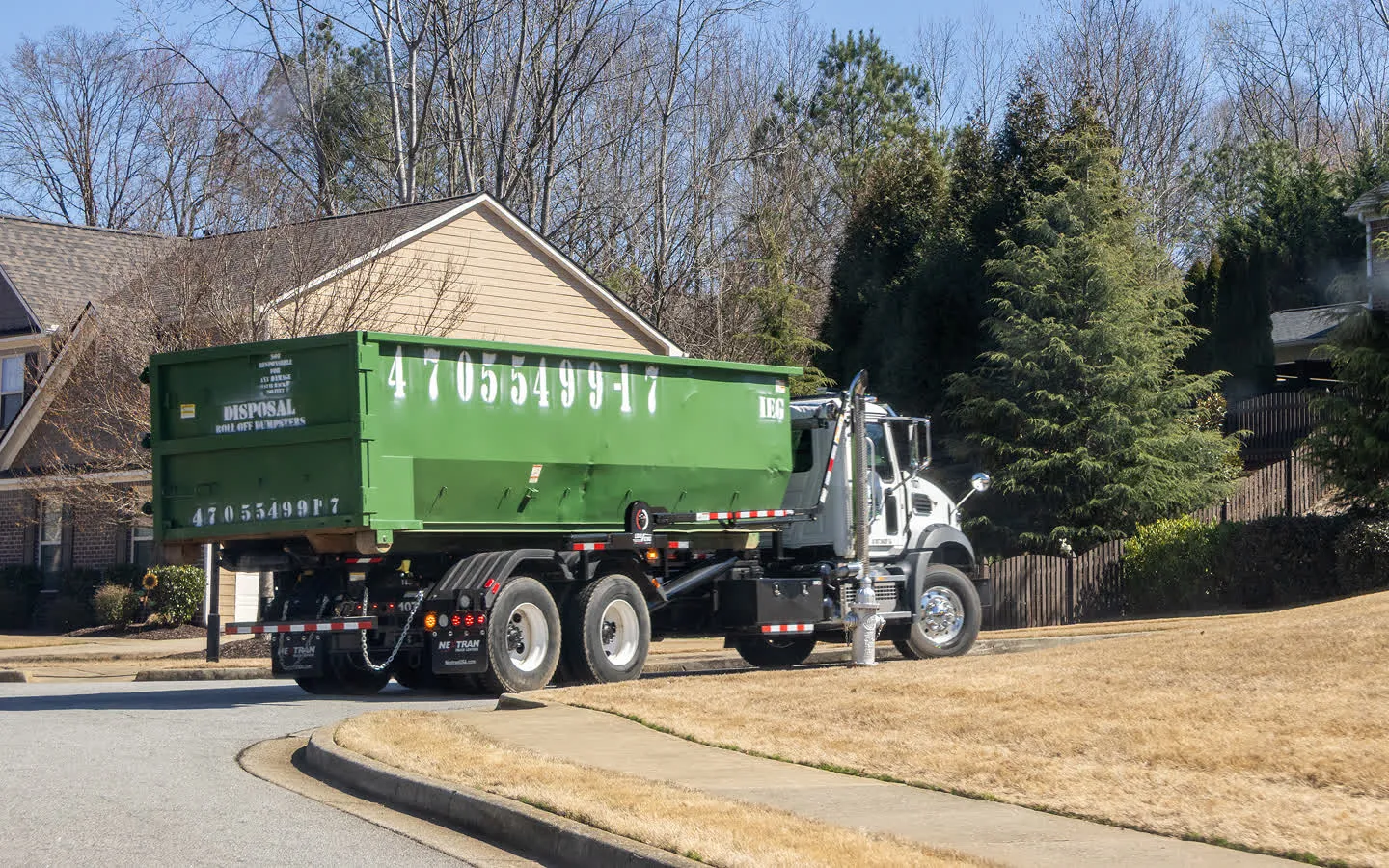 A dumpsters being dropped off in front of a house.
